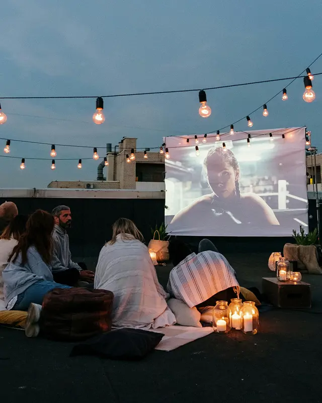 Menschen genießen einen Film unter den Sternen im Dachkino.