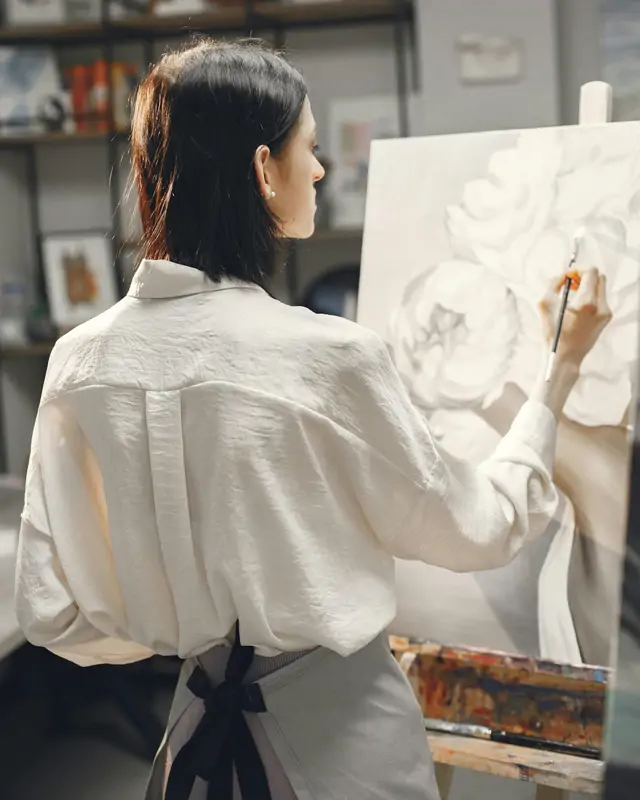 Frau vertieft sich im Malkurs ins Malen mit verschiedenen Kunstwerken.