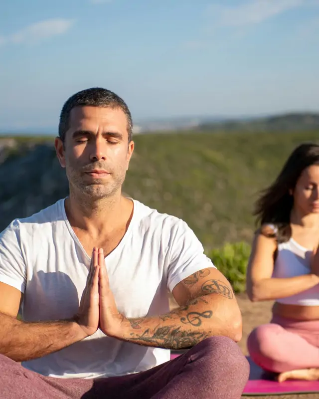 Teilnehmer meditieren im Freien bei einer ruhigen Yoga-Atempause.